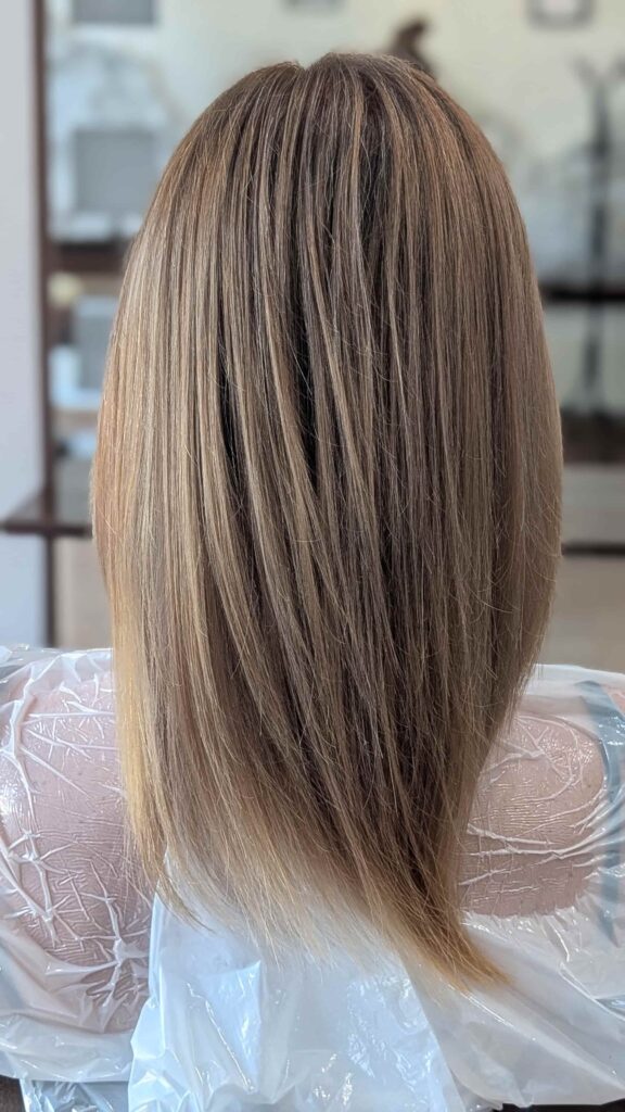 Idealnie jednolity, lśniący kolor blond na prostych, długich włosach po zabiegu pokrycia odrostu i odświeżenia koloru.
