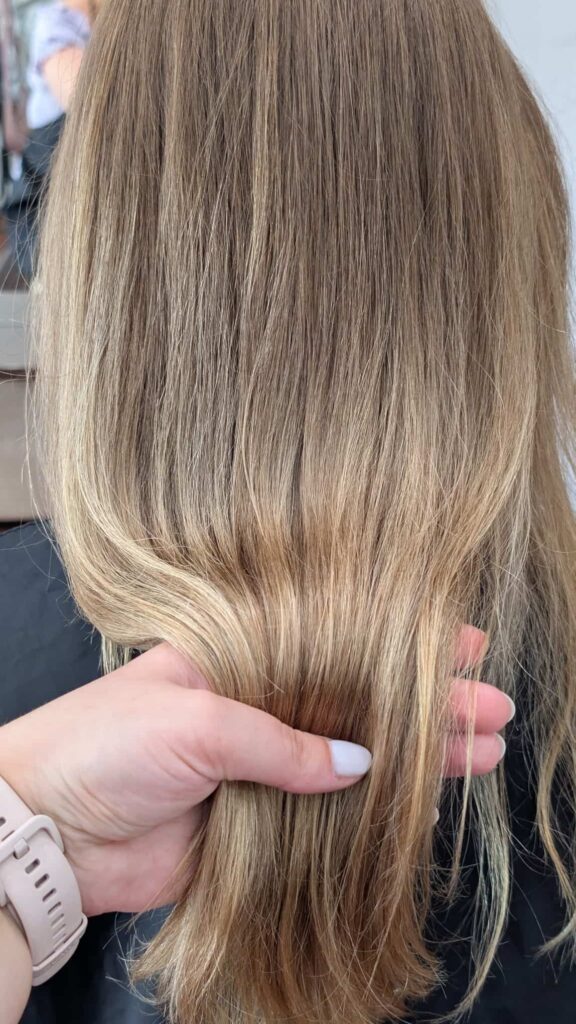 Zbliżenie na idealnie gładką i lśniącą strukturę długich włosów po zabiegu głębokiej rekonstrukcji Framesi.