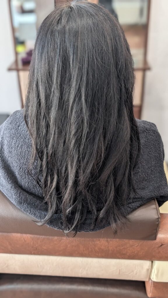 Efekt koloryzacji globalnej – długie, lśniące włosy w jednolitym odcieniu głębokiego, czekoladowego brązu.