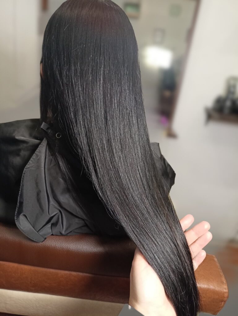 Zbliżenie na taflę idealnie gładkich, czarnych włosów, pokazujące lustrzany blask po zabiegu Framesi Restructure.