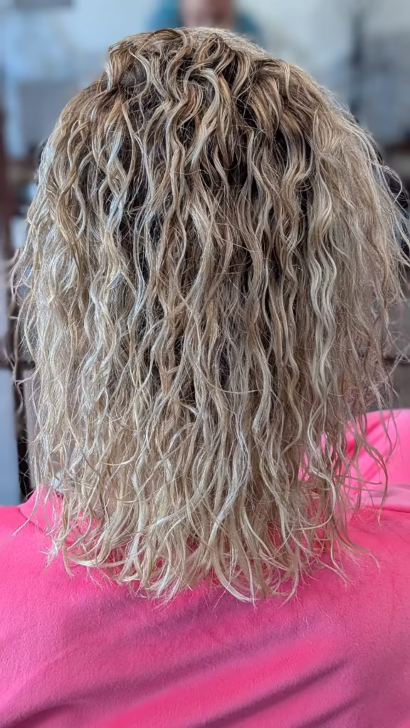 Efekt nowoczesnej trwałej ondulacji na blond włosach, tworzący naturalnie wyglądające loki i fale, wykonanej w salonie Colors w Słubicach.