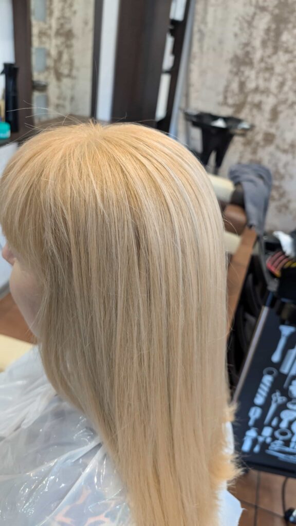 Profil klientki z idealnie gładkimi włosami w odcieniu czystego, świetlistego blondu po koloryzacji w salonie Colors Premium Słubice.