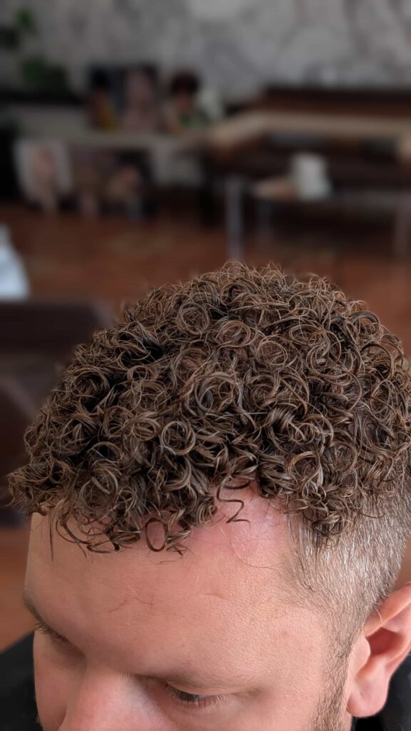 Zbliżenie na perfekcyjnie zdefiniowany, sprężysty skręt po zabiegu męskiej stylizacji permanentnej.